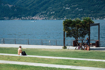People sitting at park by sea
