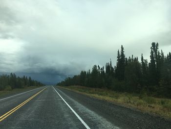 Road by trees against sky