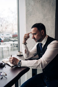 Young man using mobile phone while sitting on table