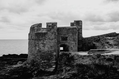 Old ruin by sea against sky