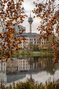 Reflection of trees and buildings in lake against sky