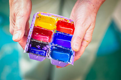 Midsection of person holding watercolor paints in palette