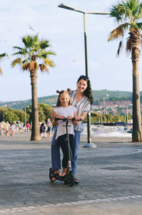 Happy family lifestyle. mother, boy, girl in city. ride scooters. laughing on a summer. fun