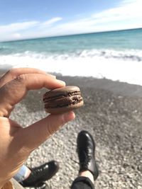 Close-up of man holding macaroon at beach