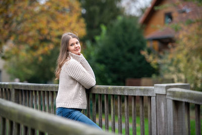 Woman smiling while standing by railing