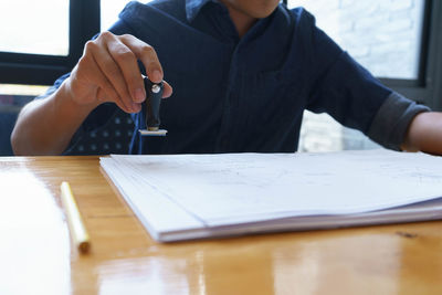 Midsection of man reading book on table