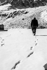 Rear view of man walking on snow covered mountain