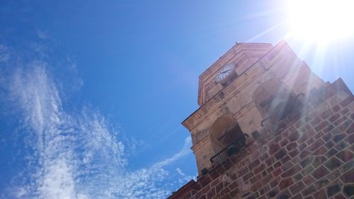 Low angle view of buildings against blue sky on sunny day