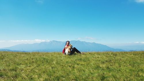 Woman sitting on field against mountain range