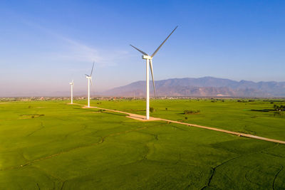 Windmills on field against sky