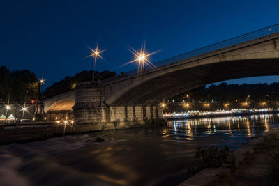 Arch bridge over tiber river against sky at dusk