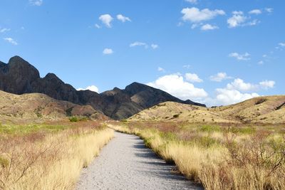 Road leading towards mountains against sky