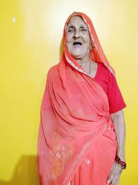 Senior woman wearing sari against yellow wall at home