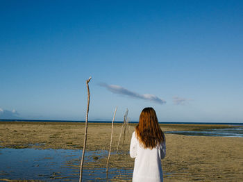 Rear view of woman standing on field against sky