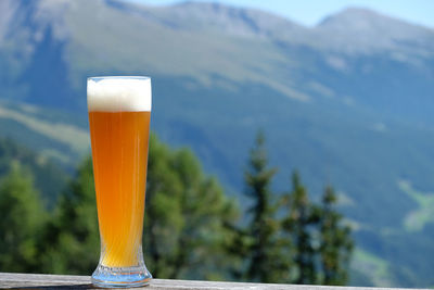 Close-up of beer glass against mountains
