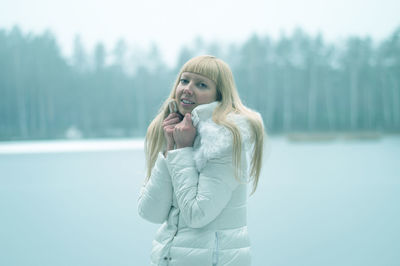 Portrait of young woman standing against lake