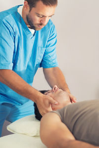 Man receiving massage therapy while lying on bed