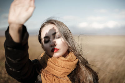 Portrait of young woman with arms outstretched standing on land