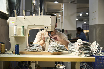 Detail of worker's hands doing sewing in the leather of the shoes at chinese shoes factory