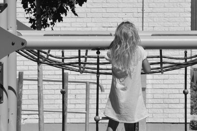 Rear view of girl standing against railing