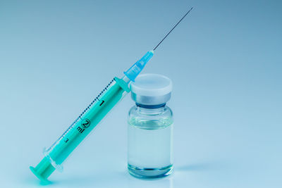 Close-up of syringe in bottle against blue background