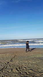 Rear view of man on beach against sky