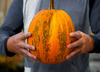 Midsection of man holding pumpkin