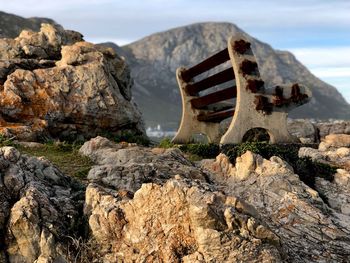 Old rusty metallic structure on rock against sky