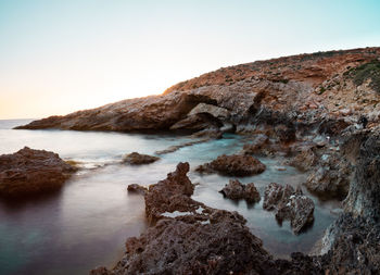 Scenic view of rocks in sea against clear sky