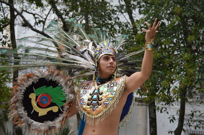 Young man wearing costume gesturing against trees