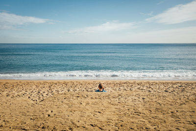 View of man relaxing at beach against sky