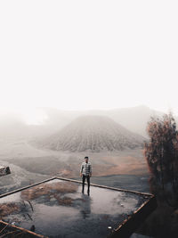 Rear view of man standing on mountain against sky