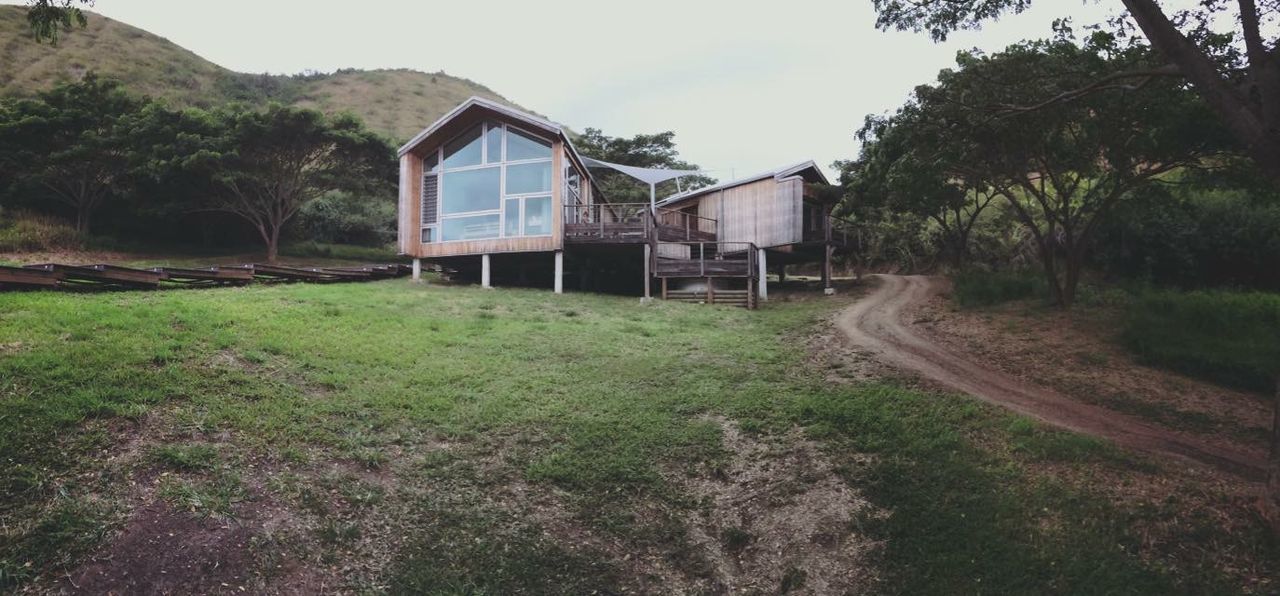 grass, house, built structure, architecture, building exterior, landscape, sky, field, tranquil scene, mountain, tranquility, dirt road, plant, nature, tree, scenics, rural scene, beauty in nature, growth, day