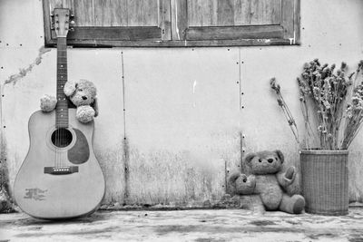 Stuffed toys by guitar against wall