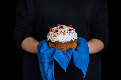 Midsection of man holding ice cream cone against black background