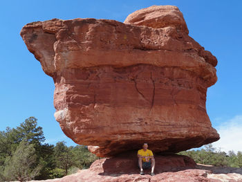 Man sitting under balanced rock at garden of the gods park in colorado springs