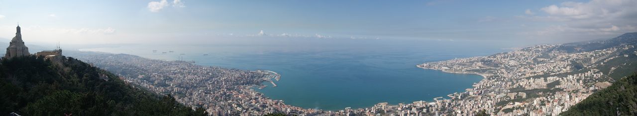 Panoramic view of sea and cityscape against sky