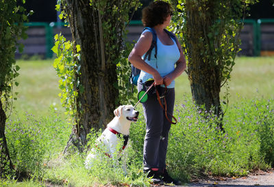 Full length of woman with dog standing in park