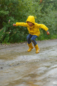 Boy jumping through muddy puddles in the rain