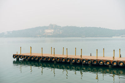 Wooden posts in river against clear sky