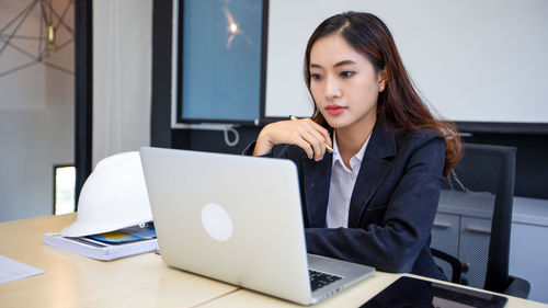 Businesswoman using laptop at desk in office