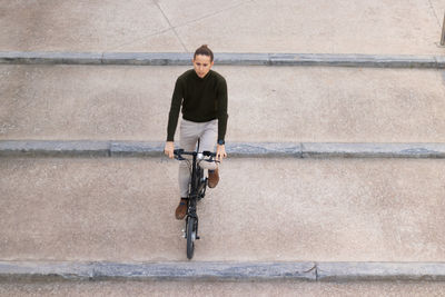 Overhead shot of young man riding a bicycle going down the stair in the financial district