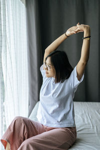 Young woman sitting on bed at home