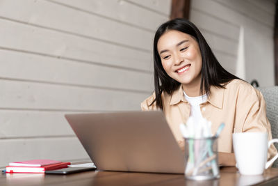 Portrait of woman using laptop while sitting on table