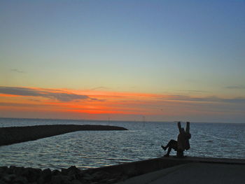 Silhouette people on beach against sky during sunset