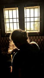 Portrait of woman smoking by window