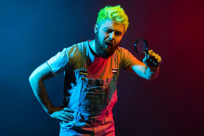 Man holding magnifying glass against colored background