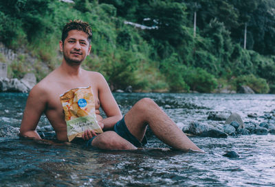 Portrait of young man sitting in water