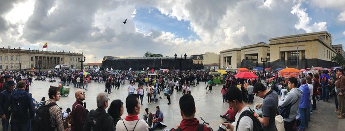 Panoramic view of people on street against cloudy sky