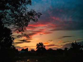 Low angle view of silhouette trees against dramatic sky